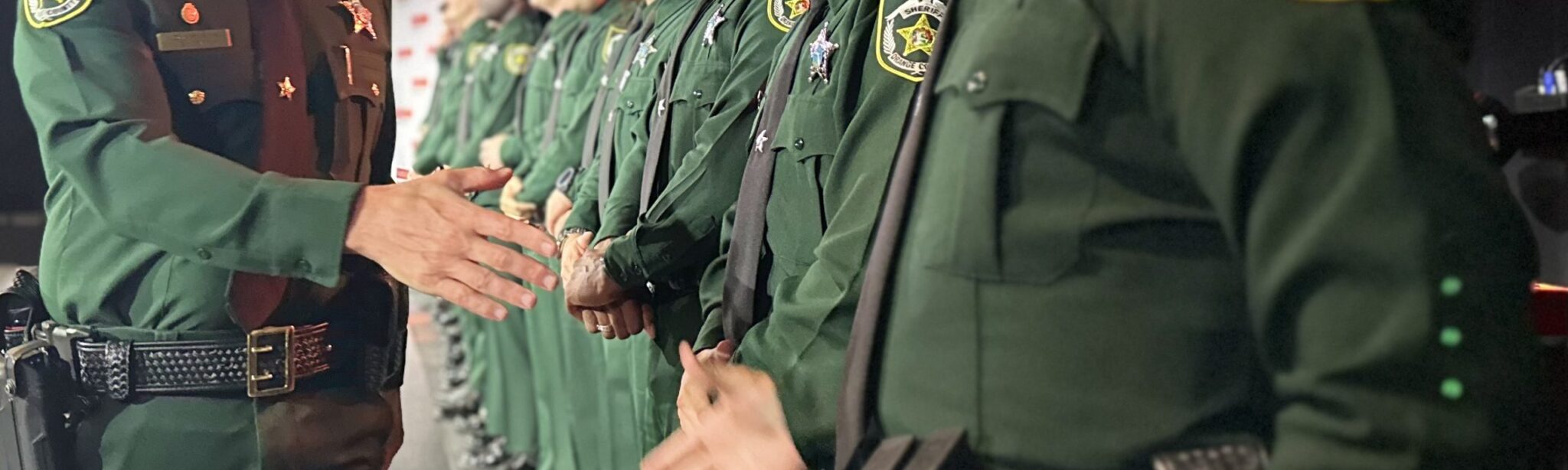 A line of new deputies shaking hands with the Sheriff